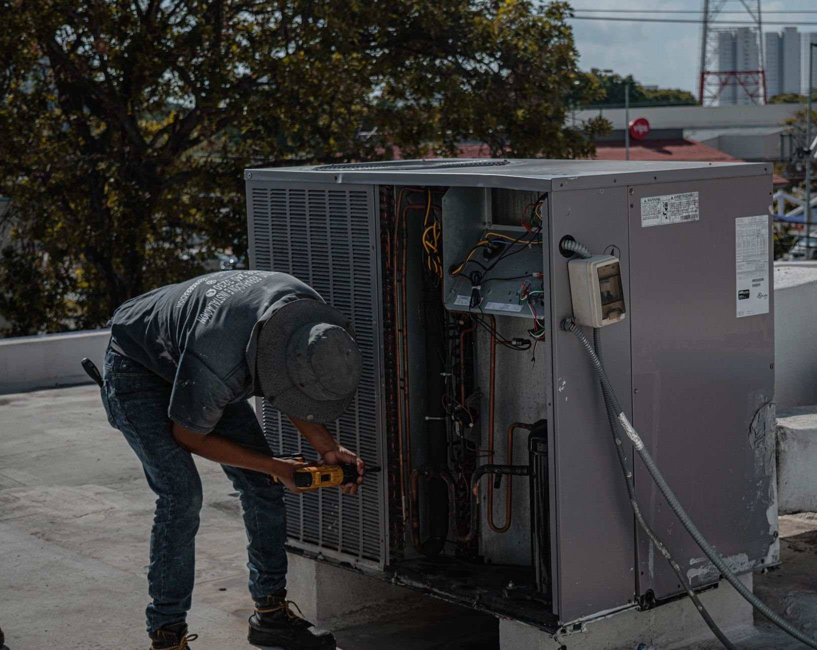 A technician repairing an air conditioning unit on a rooftop