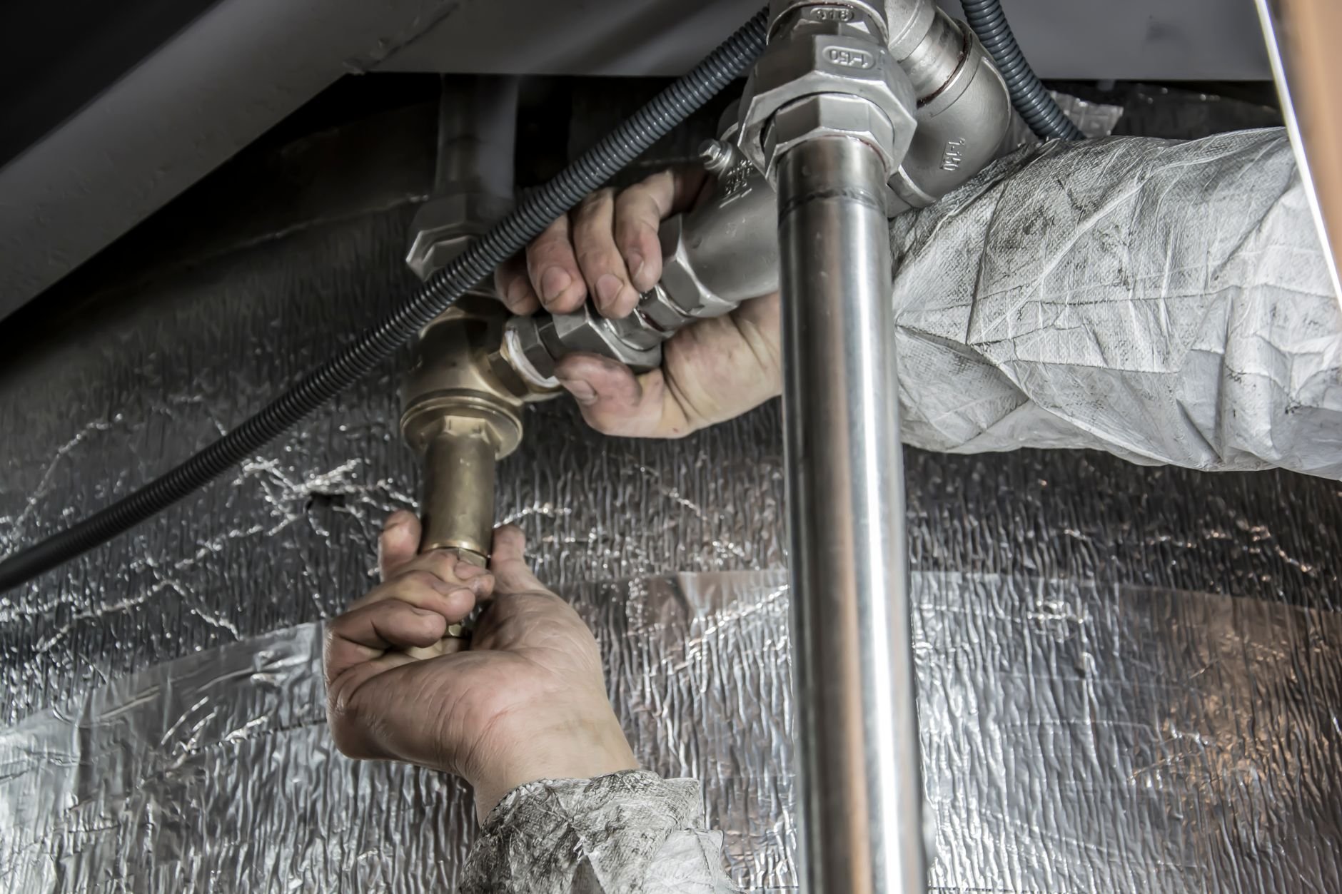 Close-up of a plumber's hands installing steel pipes
