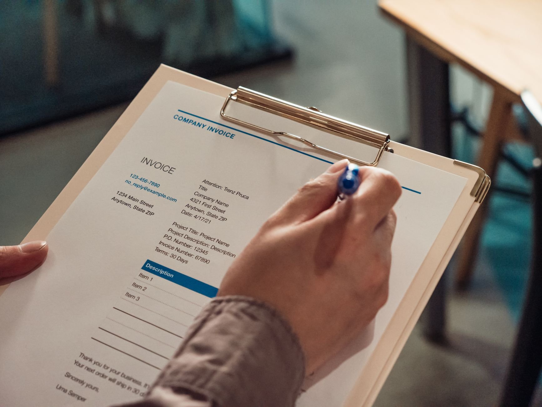 Person holding a company invoice on a clipboard